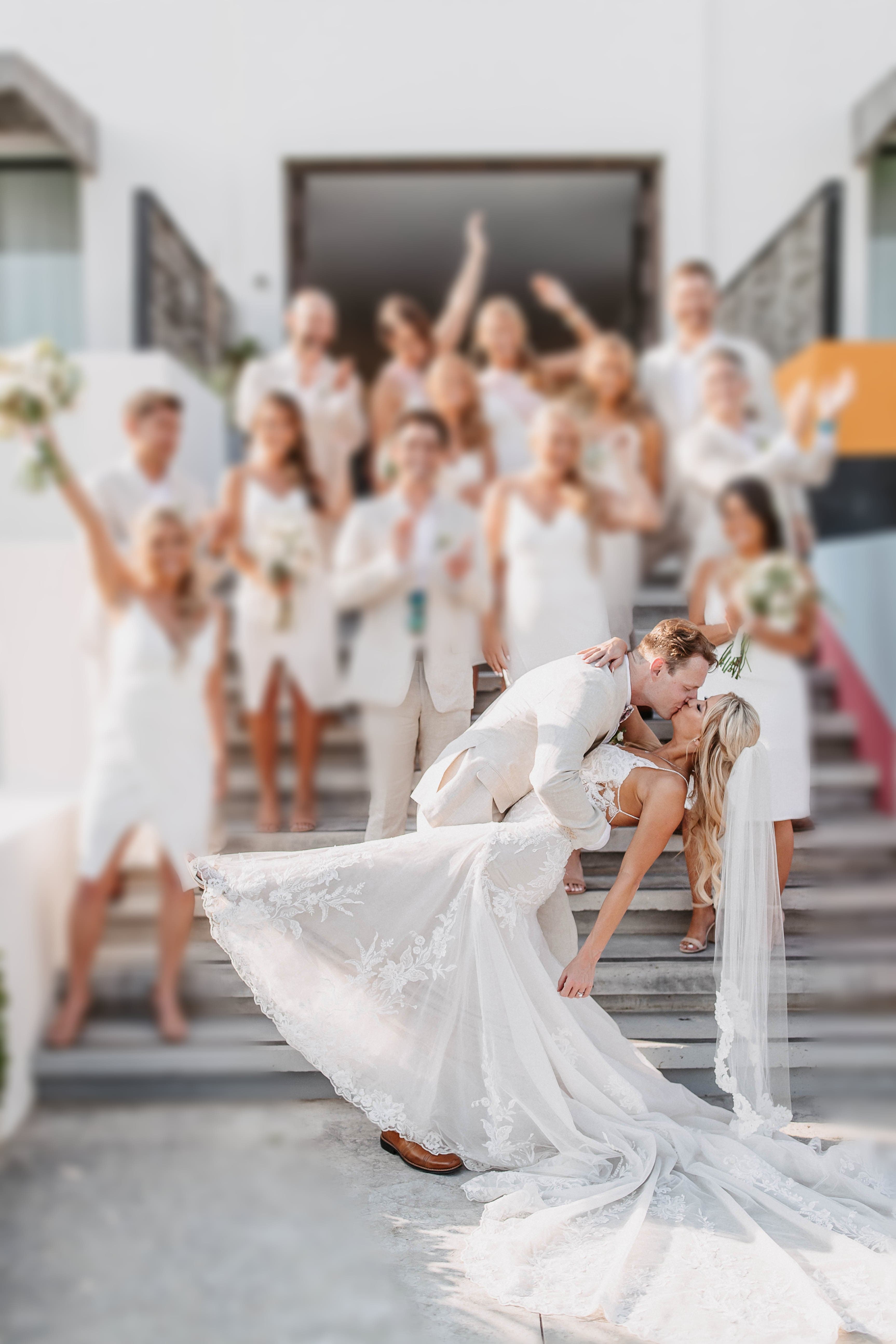 Romo dipping Jess for a kiss in front of the wedding party